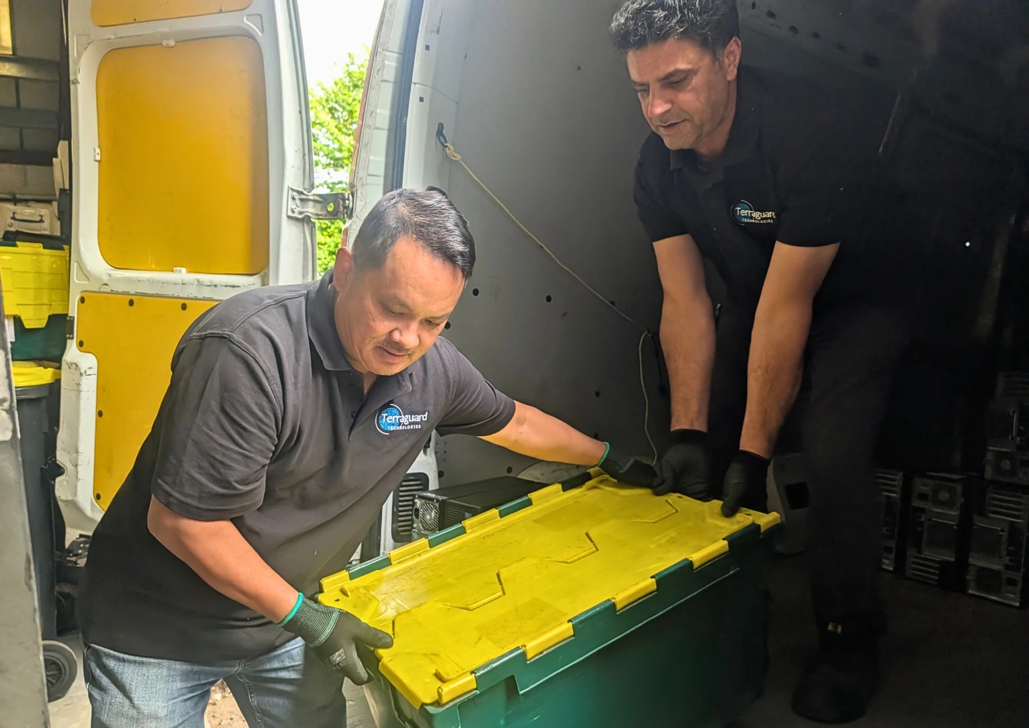 Two Terraguard staff loading a crate of retired IT equipment into the collection van