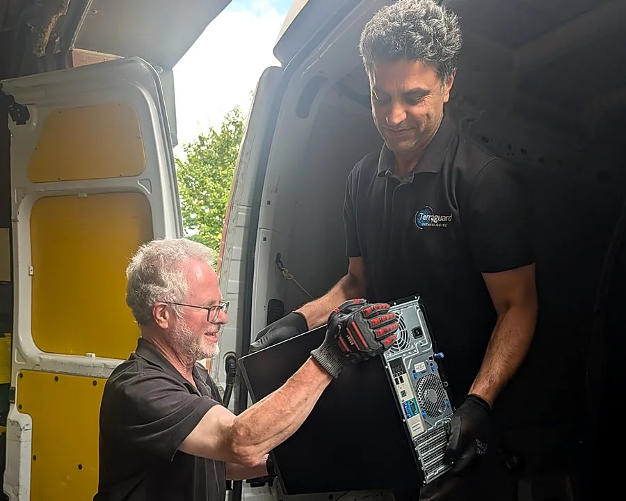 Two Terraguard staff passing a computer tower down from the collection van