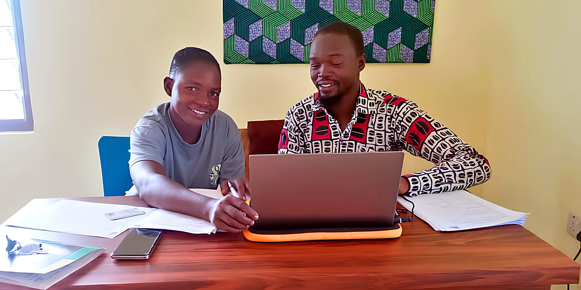 Two partner-organisation staff working together at a laptop