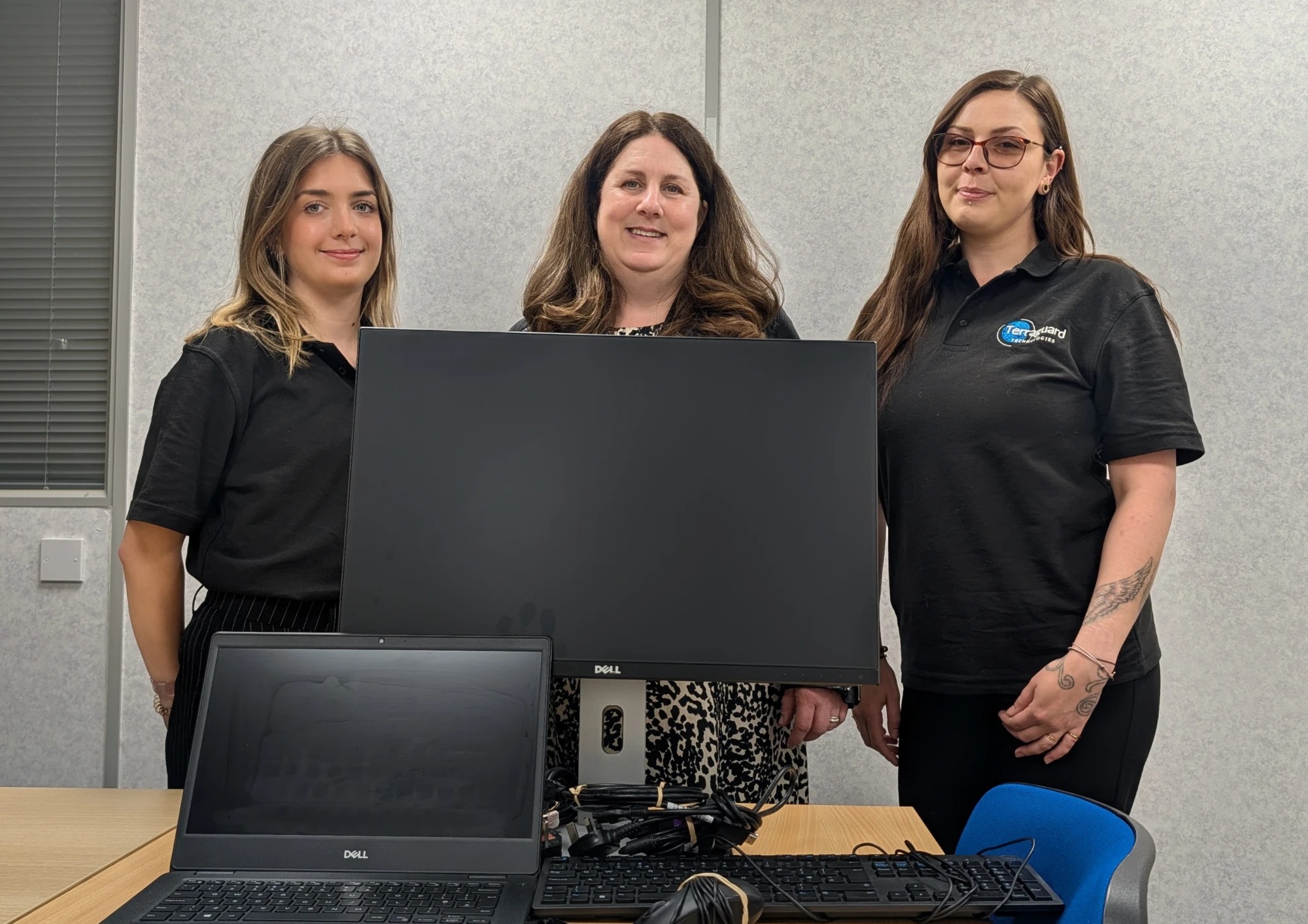 Three Terraguard staff with a refurbished monitor and laptop, ready to be rehomed