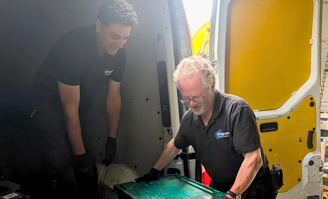 Two Terraguard staff handing a crate of equipment out of the collection van
