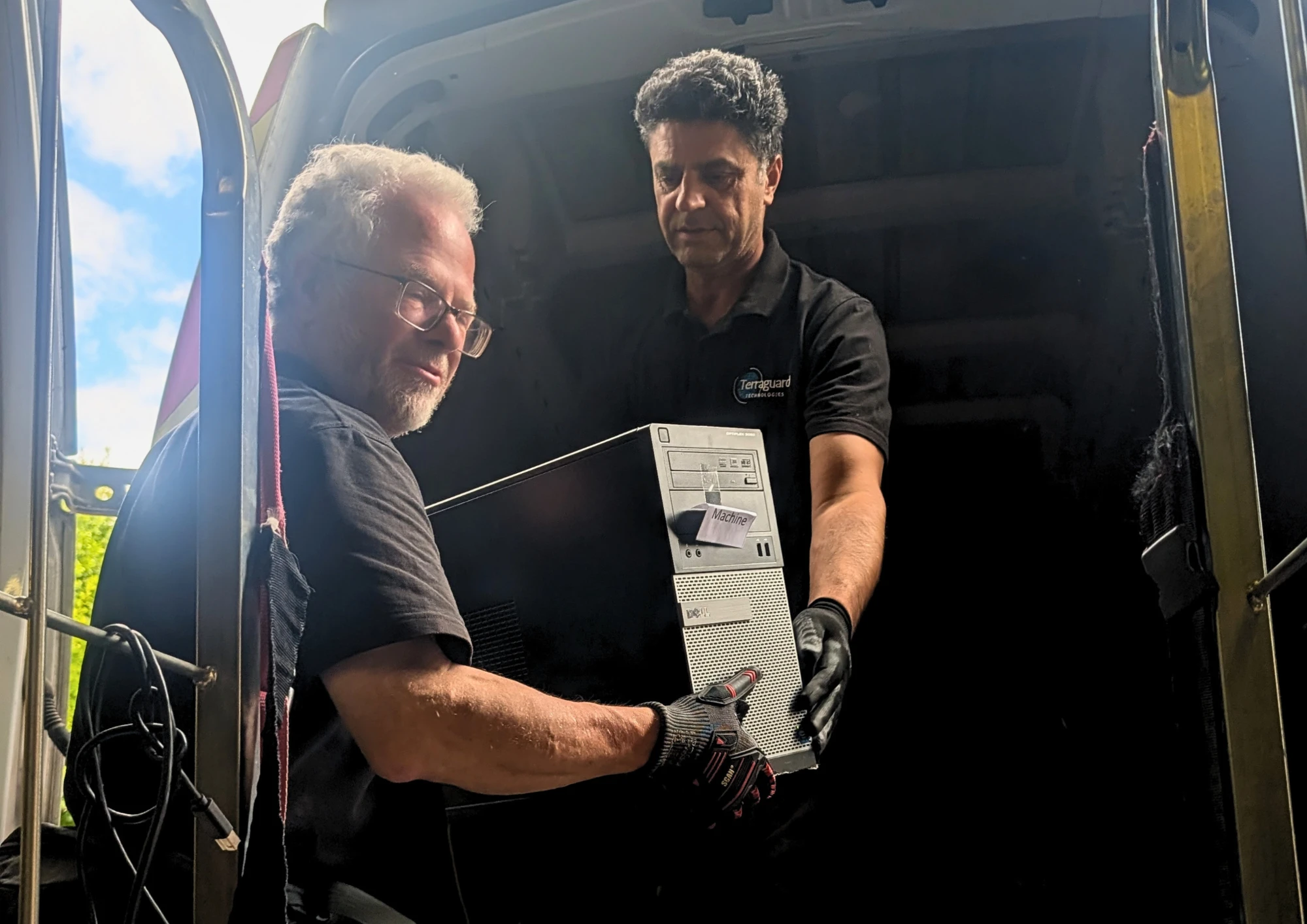 Two Terraguard staff handing a desktop tower into the collection van