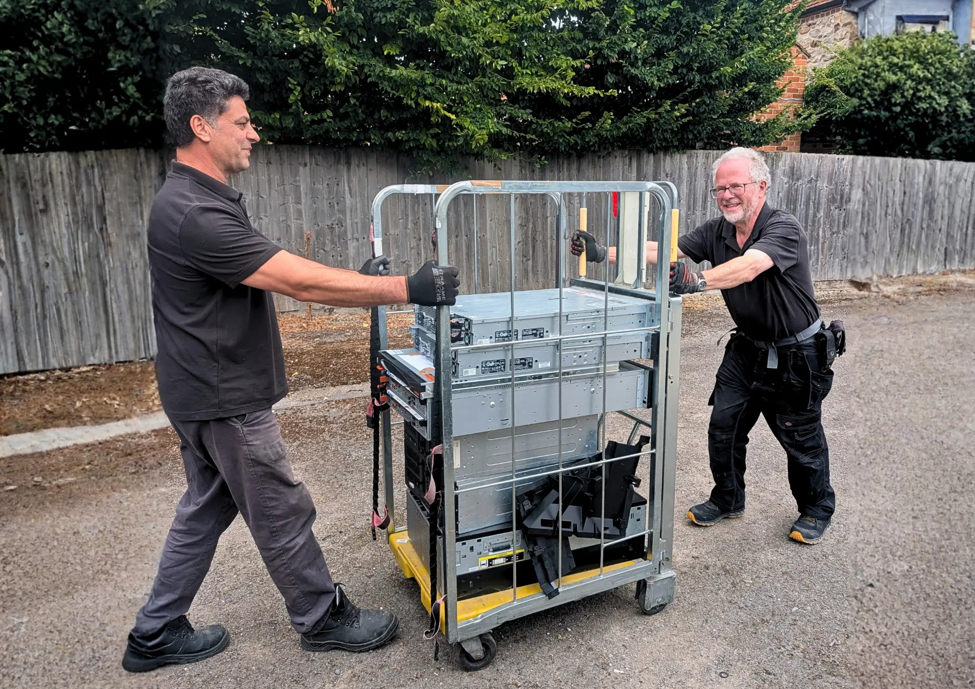 Two Terraguard staff wheeling a loaded server cage out to the collection van