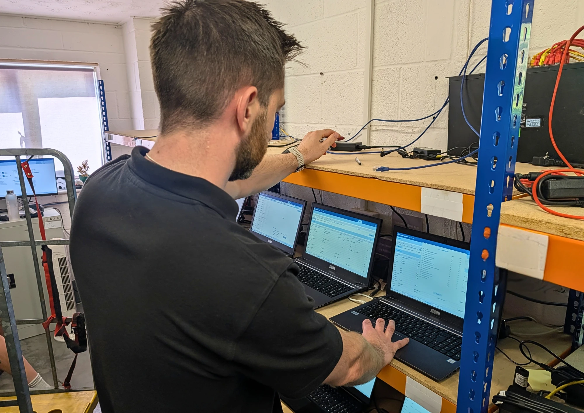 A Terraguard technician working on a row of laptops on the workshop bench